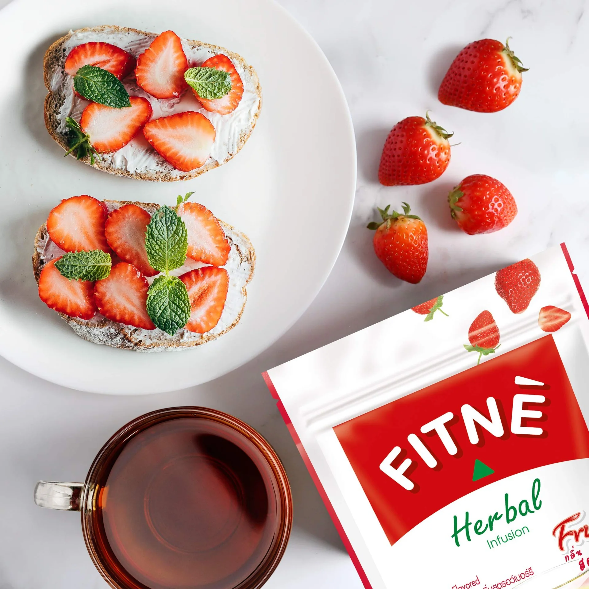 Hộp trà thảo mộc túi lọc Fitné với dải băng đỏ trên nền xanh tự nhiên